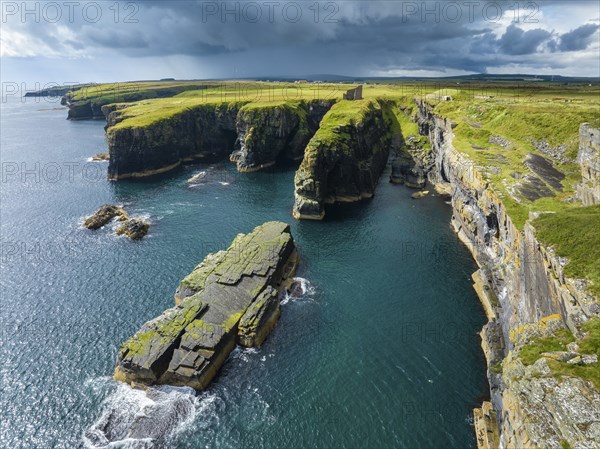 Aerial view of the ruined Castle of Old Wick surrounded by rugged cliffs on the North Sea coast,