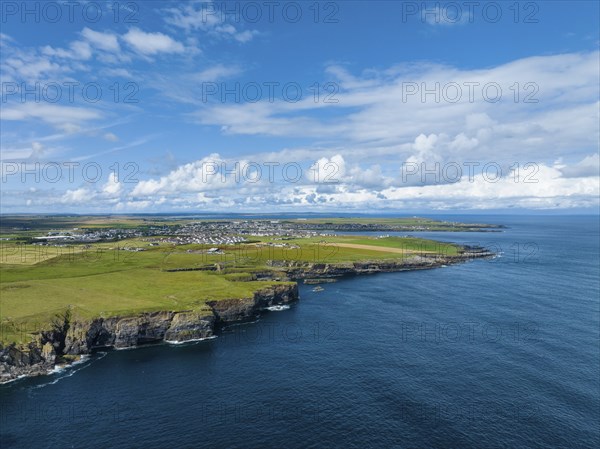 Aerial view of rugged cliffs on the North Sea coast, with the harbour town of Wick on the horizon,