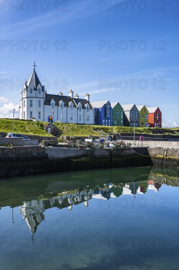 Holiday homes reflected in the ferry harbour of John o' Groats, County Caithness, Scotland, United