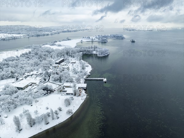 Aerial view of the snow-covered Mettnau peninsula with the Mettnau park, spa centre and beach café,