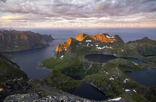 View over mountain peaks and sea, dramatic sunset, from Hermannsdalstinden, with lakes