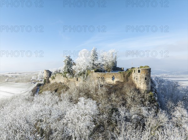 Aerial view of the snow-covered Hegau volcano MÃ¤gdeberg, with remains of a castle wall, surrounded