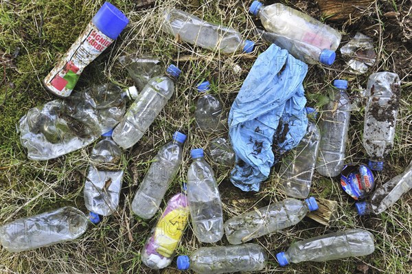 Discarded plastic bottles and other non-degradable rubbish in field