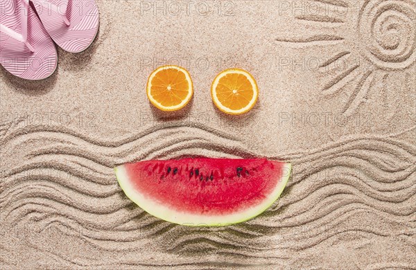 Summer wallpaper, drawing on sand, sea waves and sun, face shape of summer fruits, pink flip-flops,