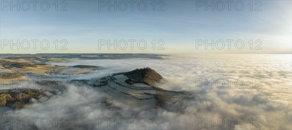 Aerial panorama of the wintry and fog-covered Hegaulandschaft shortly after sunrise, the volcanic