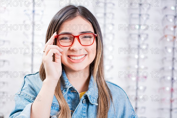 Happy teen girl in eyeglasses on a background of optical store. Happy female customer modeling