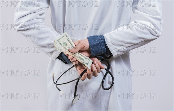 Medical corruption and bribery concept. Corrupt doctor hiding money back, Dishonest doctor hiding