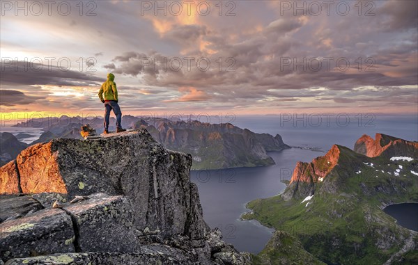 View over mountain top and sea, dramatic sunset, climbers at the top of Hermannsdalstinden, with