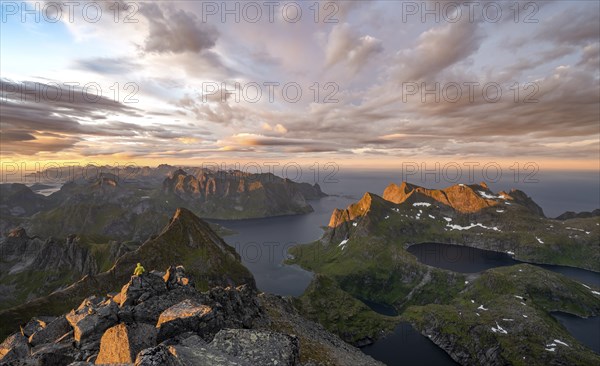 View over mountain peaks and sea, dramatic sunset, mountaineers at Hermannsdalstinden, with lakes