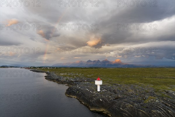Small lighthouse at the coast, behind the mountain range Seven Sisters, light mood with rainbow,
