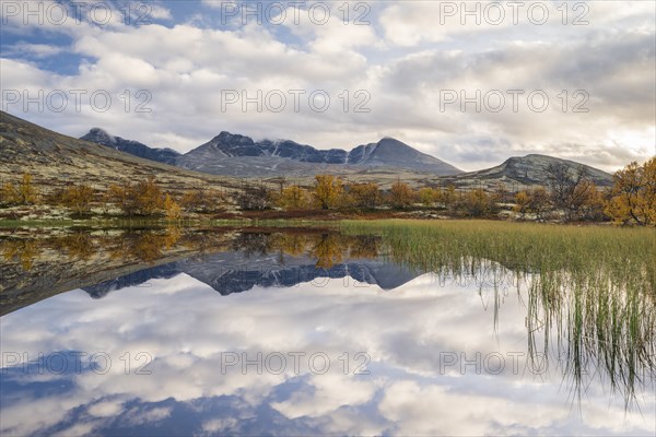 Reflection of the autumn landscape in Rondane National Park, mountains Hogronden, Midtronden and