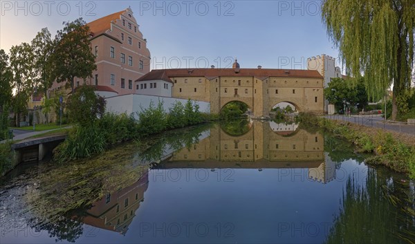 An old fortification wall town spectacle is perfectly reflected in the calm waters of the river