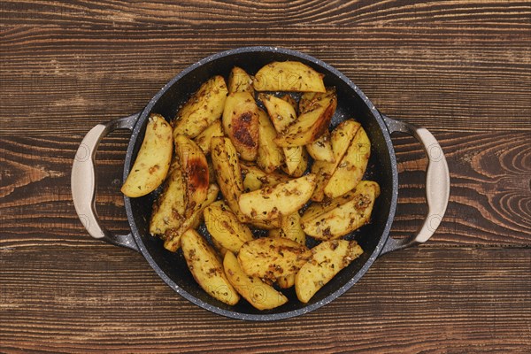 Potato wedges roasted in oven with thyme and salt, top view