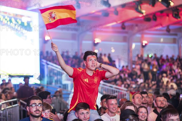 Fan of the Spanish team waving a flag at the Adidas fan zone at the Bundestag during the final
