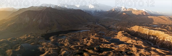 PanoramaWhite glaciated and snow-covered mountain peak Pik Lenin at sunrise, hilly landscape with
