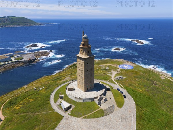 Ancient lighthouse on a land mass surrounded by crystal blue ocean and green vegetation under a
