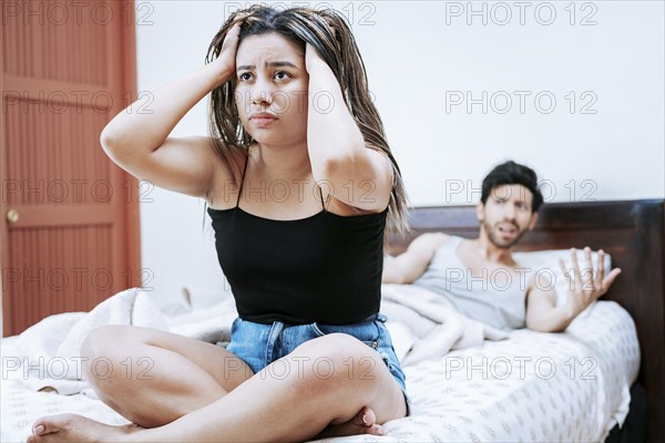 Young couple arguing sitting on the bed. Couple problems in bed. Upset woman with husband sitting