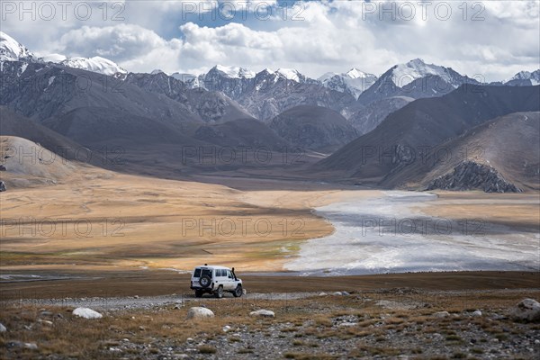Off-road vehicle on a gravel track, glaciated and snow-covered peaks, Ak Shyrak Mountains, near