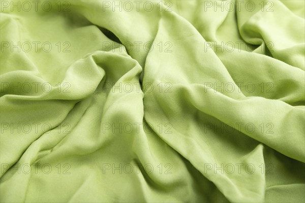 Fragment of green linen tissue. Side view, natural textile background and texture. wave concept,