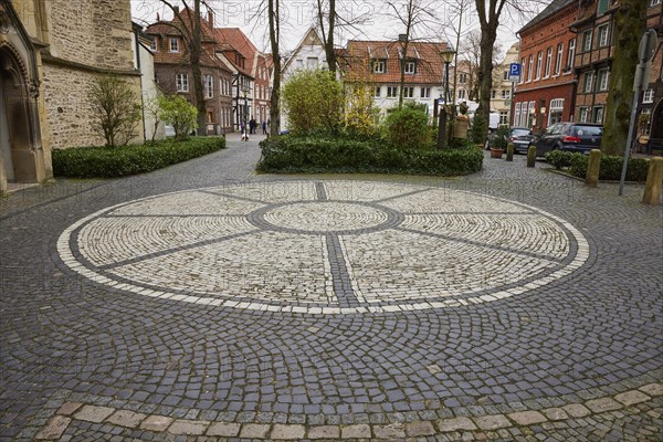 Rosette of white cobblestones at St Laurentius Church with historic houses and trees in the