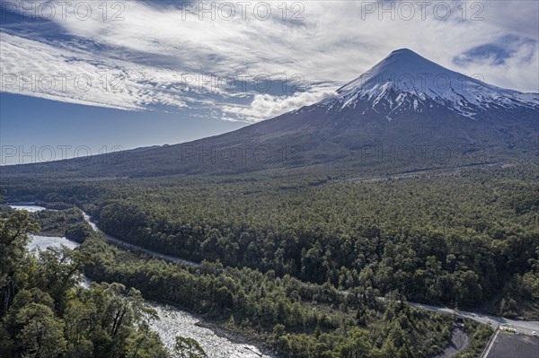 Snow-capped volcano Osorno rising high above river Rio Petrohue, early spring, chilenean lake