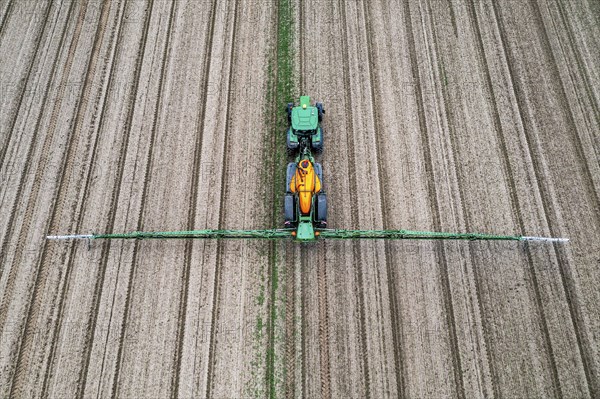 Farmer working a field, crop protection agent being sprayed, field with young sugar beet plants,