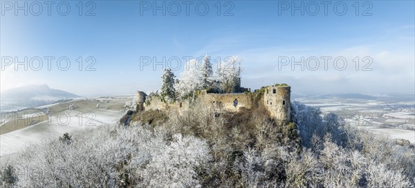 Aerial view of the snow-covered Hegau volcano MÃ¤gdeberg, with remains of a castle wall, surrounded