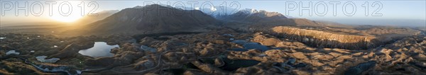 Panorama, White glaciated and snow-covered mountain peak Pik Lenin at sunrise, hilly landscape with