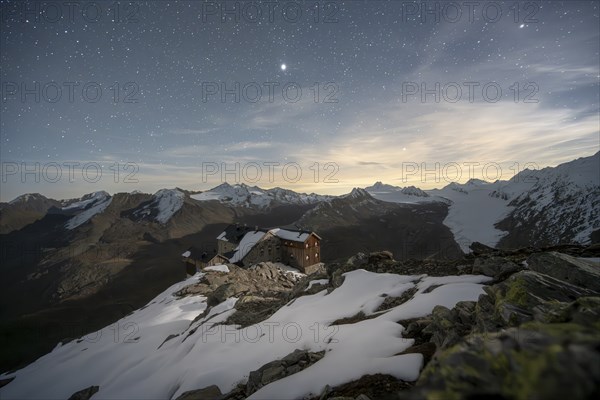 Mountain landscape under a starry sky, night shot, mountain hut Ramolhaus in autumn with snow, view