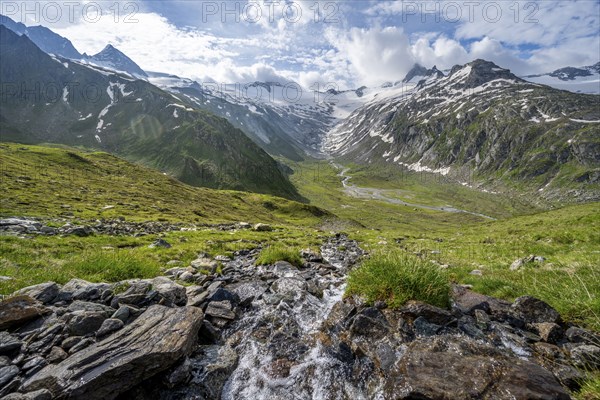Picturesque mountain landscape with mountain stream, mountain summit with snow and glacier