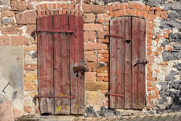 Weathered wooden doors to stable and loo, with heart, façade made of sandstone, natural stone,