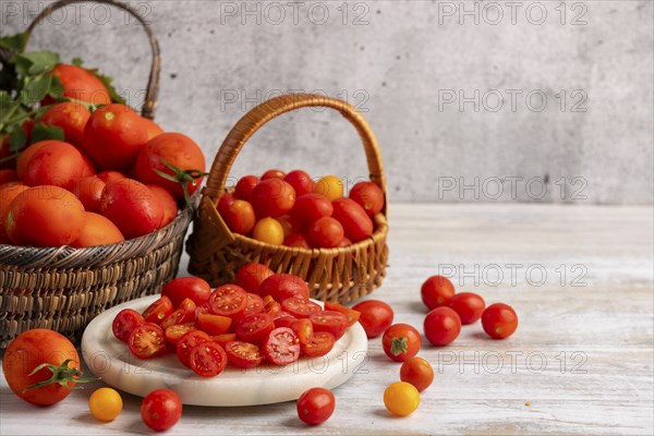 Sliced tomatoes on a white marble slab, surrounded by fresh tomatoes in baskets