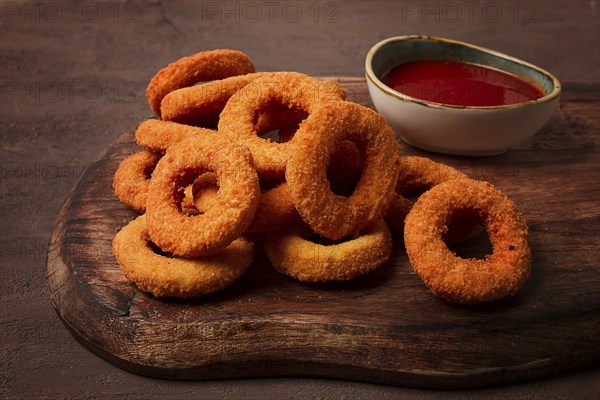 Crispy chicken rings, fried, on a wooden board, close-up