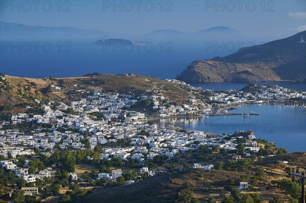 White painted houses of a coastal town, embedded in hilly landscape, surrounded by blue sea, Skala,