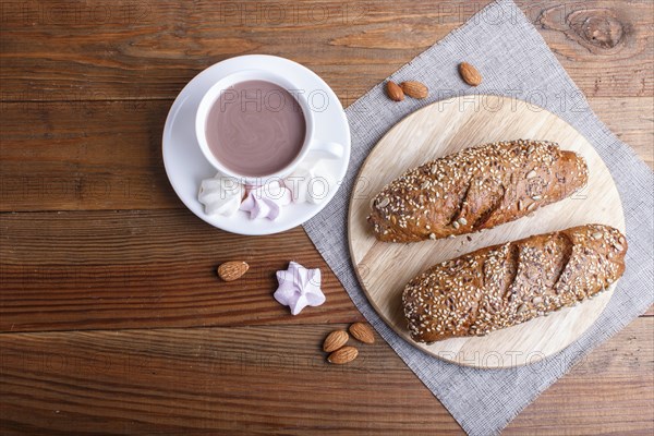 Rye bread with sunflower seeds, sesame and flax with cup of cocoa on brown wooden background. top