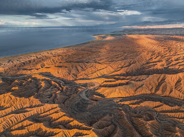 Landscape of eroded hills, badlands at sunset, Issyk Kul Lake in the background, aerial view,