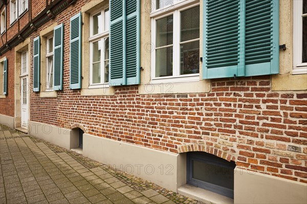Windows with blue-green shutters on a brick house in Warendorf, Warendorf district, North