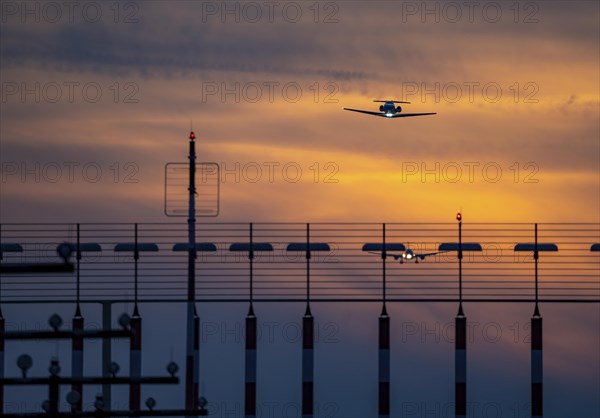 Runway lighting, approach aids, at Düsseldorf International Airport, sunset, aircraft taking off