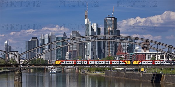 Main with regional railway on the Deutschherrnbrücke and a cargo ship in front of the skyline of