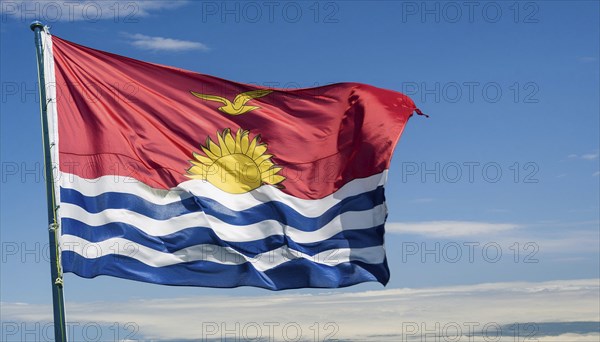 The flag of Kiribati, Polynesia, flutters in the wind, isolated against a blue sky