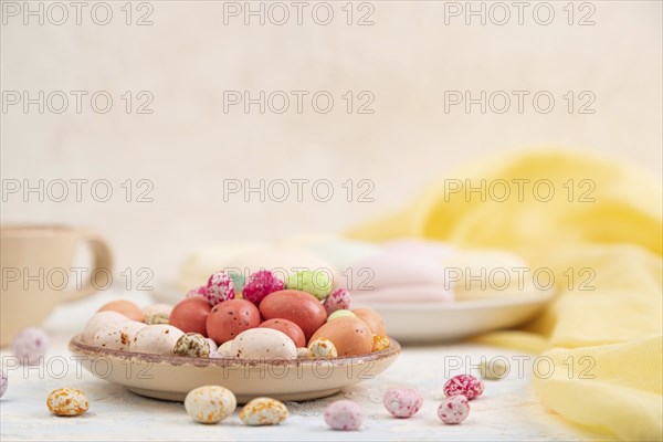 Colored dregees with cup of coffee on white concrete background and yellow textile. Side view, copy