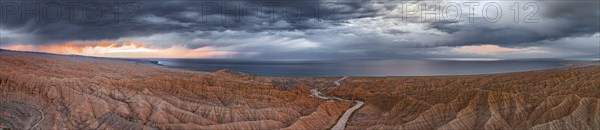 Panorama, landscape of eroded hills, badlands at sunset, Issyk Kul Lake in the background, aerial