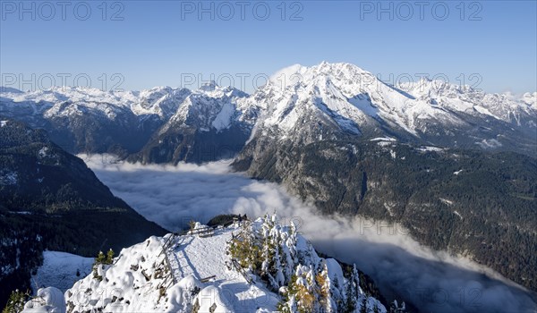 Tourist with camera on a hiking trail, Snow-covered summit of the Jenner with viewing platform in