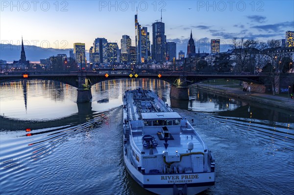Skyline of the city centre of Frankfurt am Main, river Main, dusk, Ignatz-Bubis-Bridge, cargo ship,