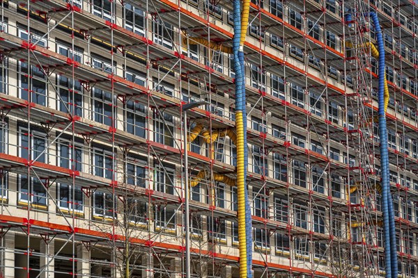 Large construction site, scaffolded shell of an office building complex, air hoses for building