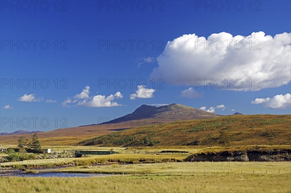 A mountain rises above a peaceful meadow under a clear blue sky, autumn, October, Highlands,