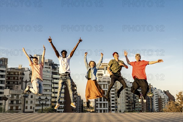 Group of young beautiful multiethnic man and woman friends having fun jumping outdoor in the city,