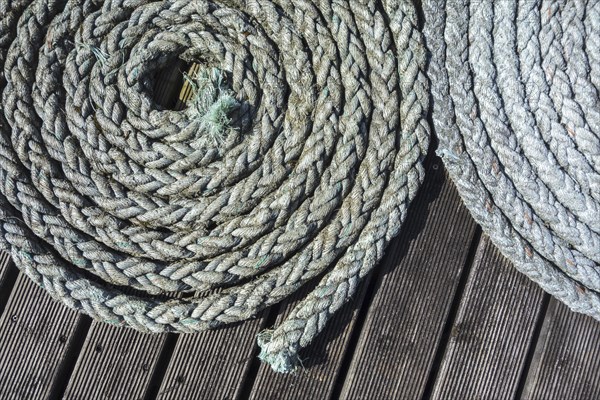 Close up of two coiled braided ropes, plaited hawsers on deck