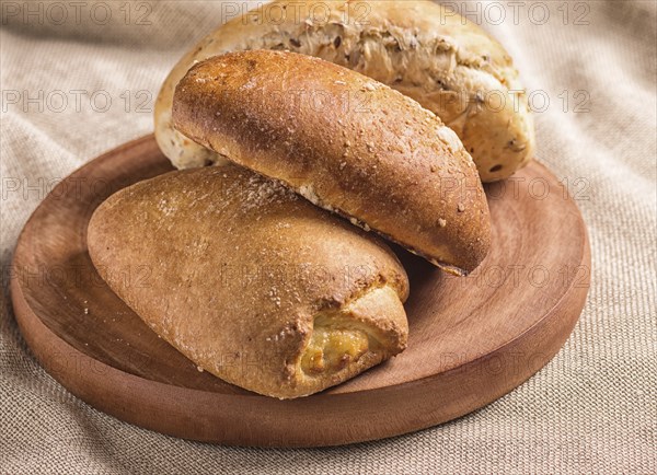 Sweet buns on a wooden board and linen tablecloth