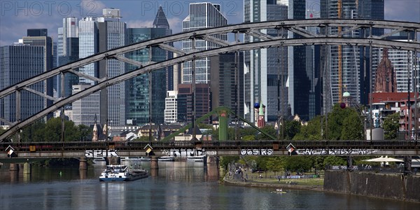 The river Main with the Deutschherrnbrücke bridge and a barge in front of the skyline of Frankfurt